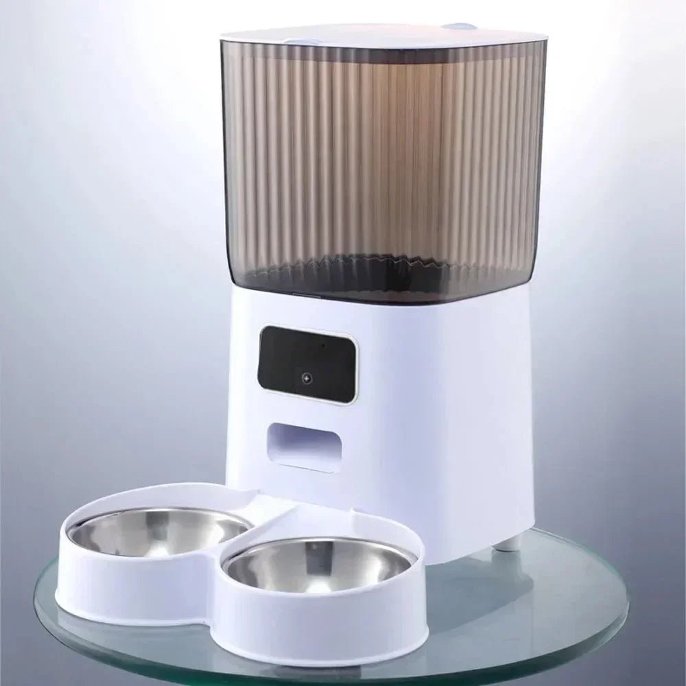 Automatic pet feeder with dual stainless steel bowls and HD camera, shown on glass surface with modern white design
